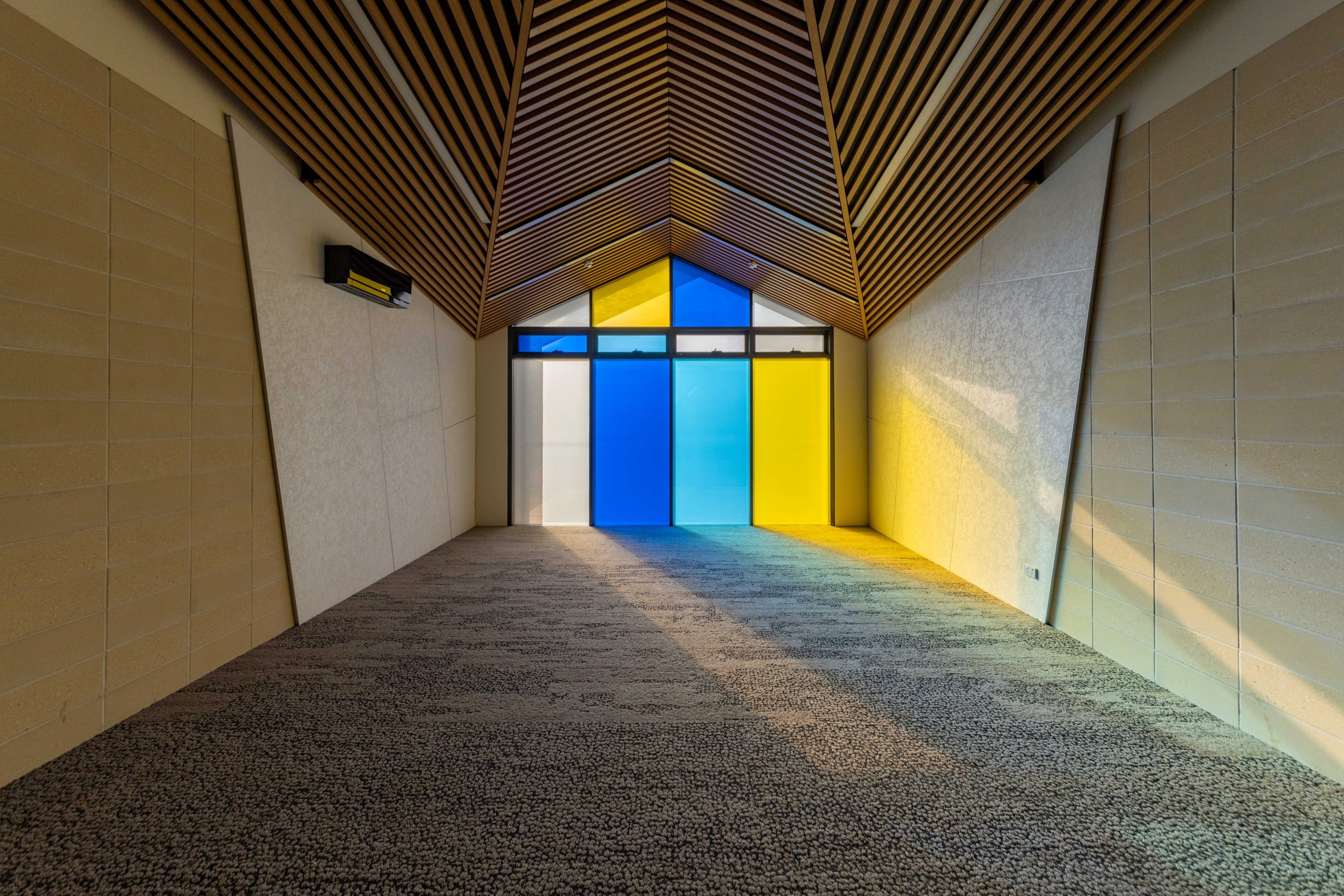 Completed EAC Multi Purpose Centre interior with timber ceiling and blue and yellow glazing